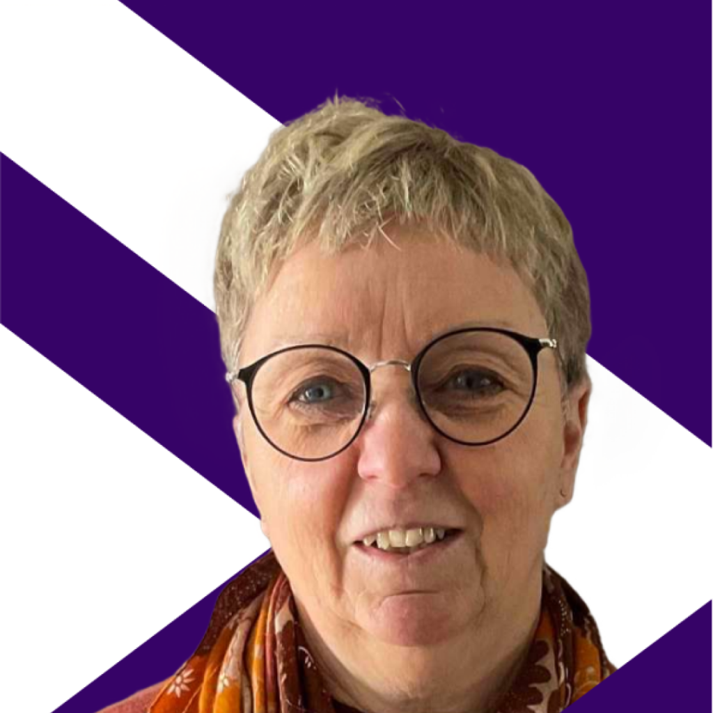 Johanne Dupre, Conseil scolaire catholique MonAvenir wearing big dark-framed reading glasses, dressed in a maroon sweatshirt and wearing an orange printed triangular scarf around her neck.