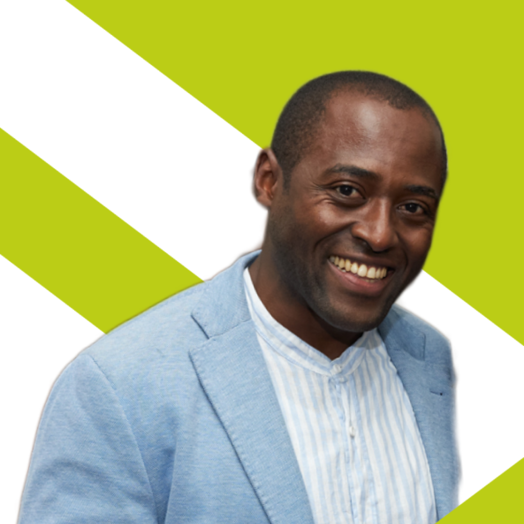 Geradoux Sigoue, Smoky Hazel, smiling, wearing a striped, formal white shirt and a blue linen blazer.